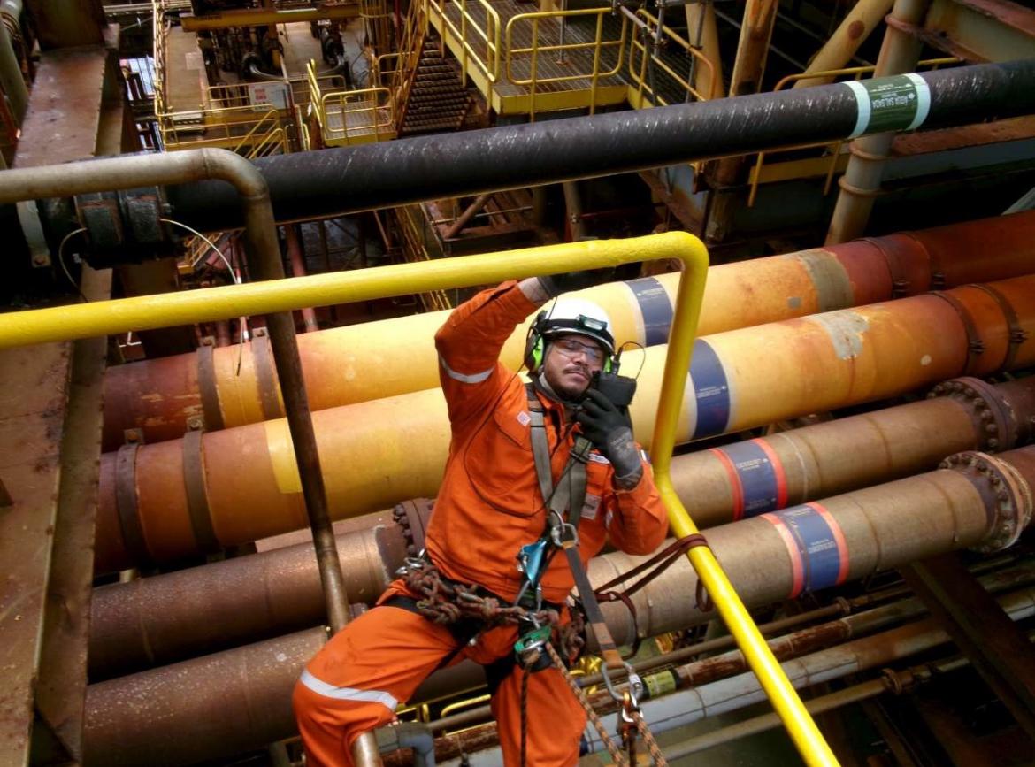Técnico em acesso por cordas sobre linhas de processo em plataforma offshore